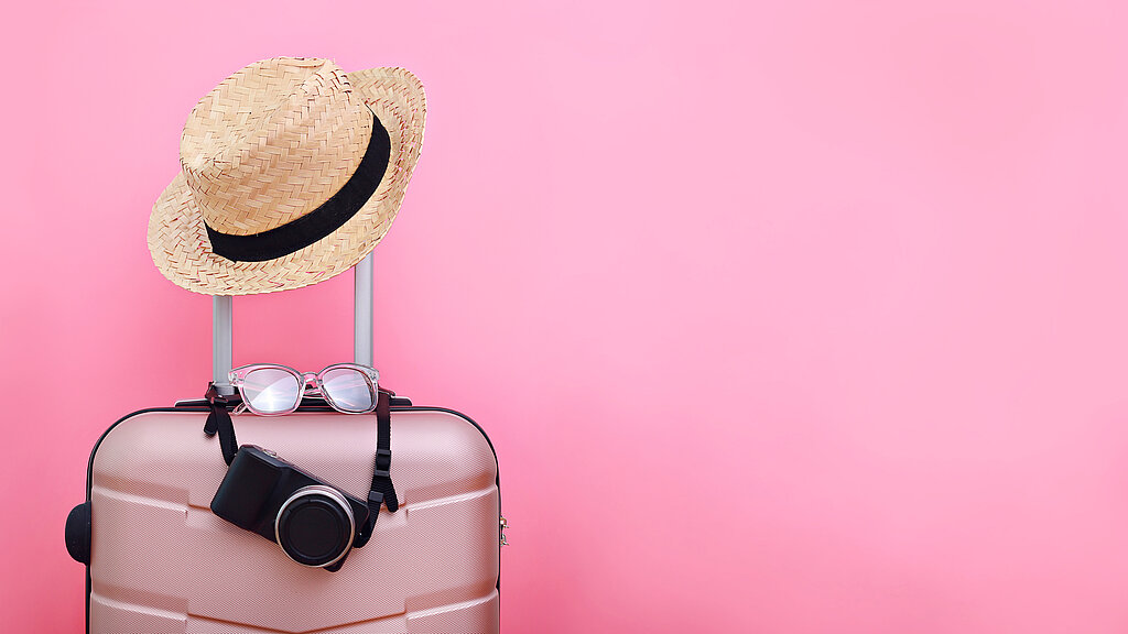 Luggage With Hat Against Pink Background