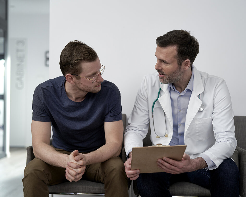 Mature doctor discussing with man at clinic