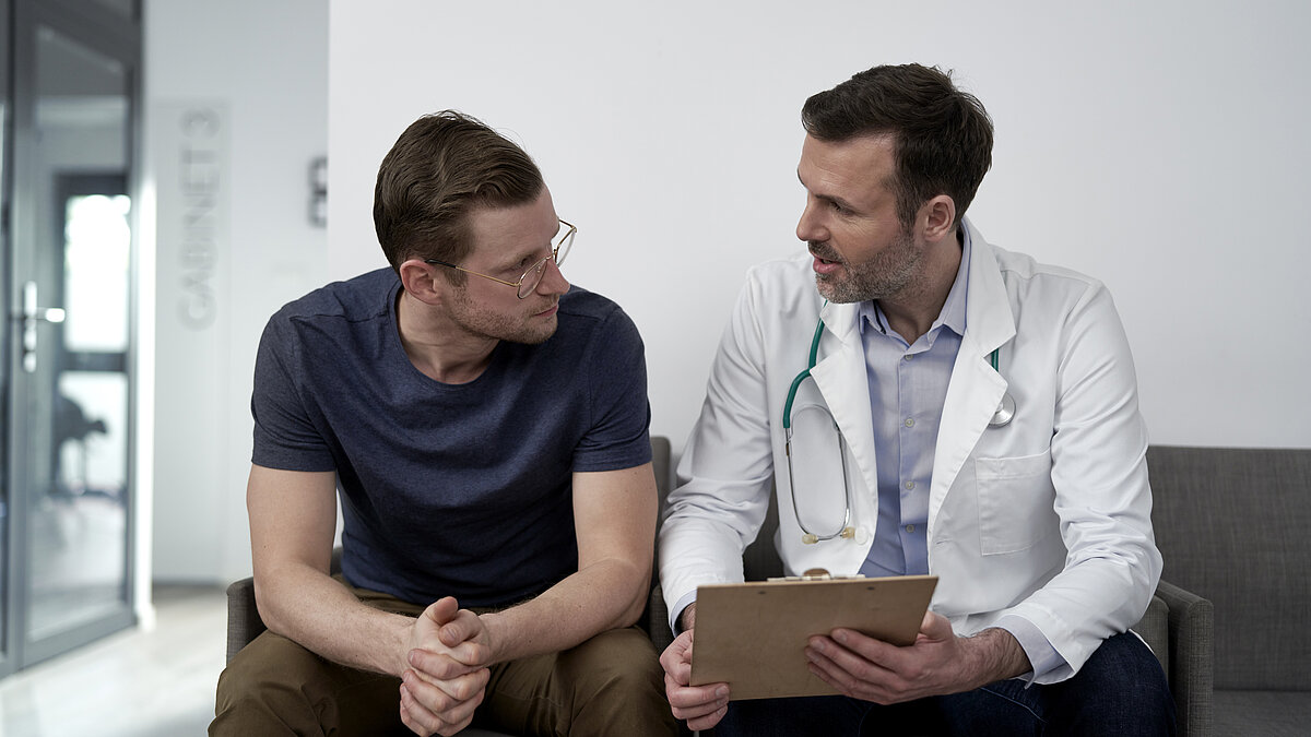 Mature doctor discussing with man at clinic