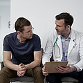 Mature doctor discussing with man at clinic