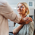 Senior Woman Supported by Male Friend in Modern Home Interior