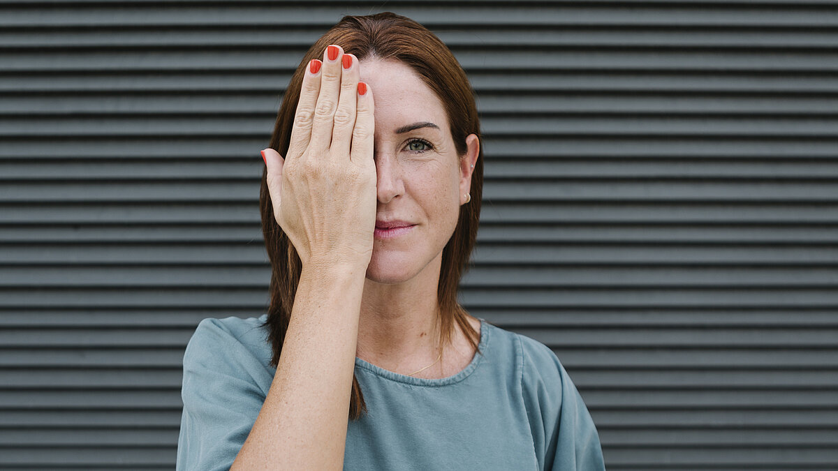 Woman covering one eye with her hand