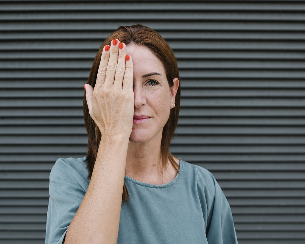 Woman covering one eye with her hand