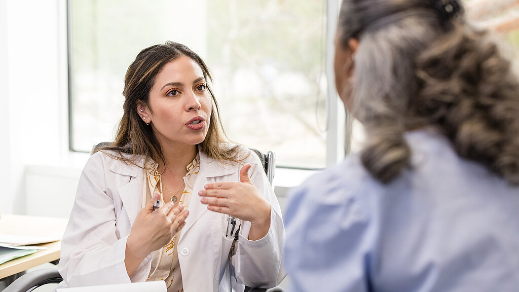 Mid adult female doctor gestures while explaining her recommendation to the patient