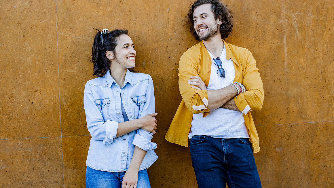 Portrait of cute couple leaning on the wall and looking at each other