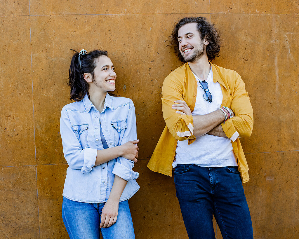 Portrait of cute couple leaning on the wall and looking at each other