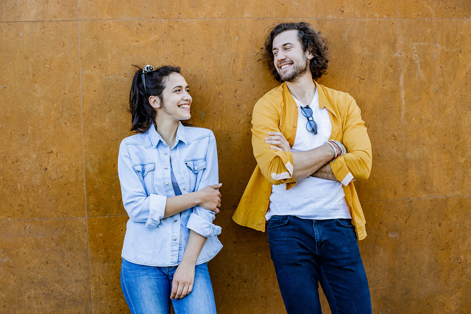 Portrait of cute couple leaning on the wall and looking at each other