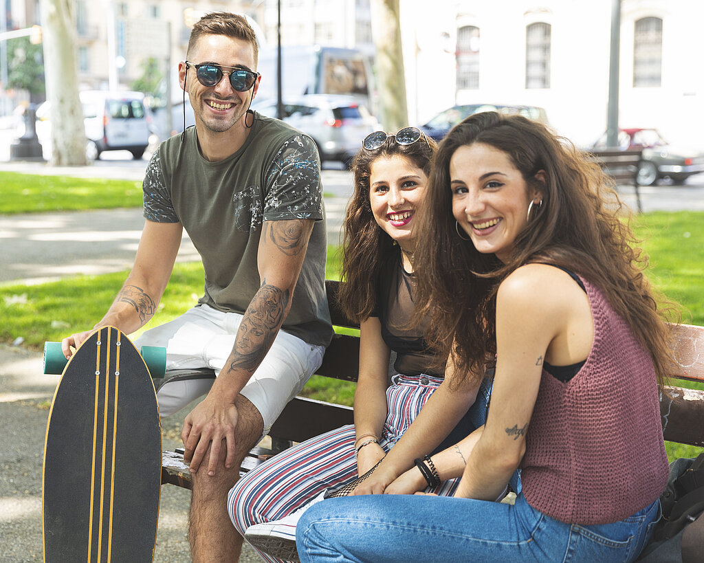 Portrait of three happy friends with skateboard relaxing in an urban park