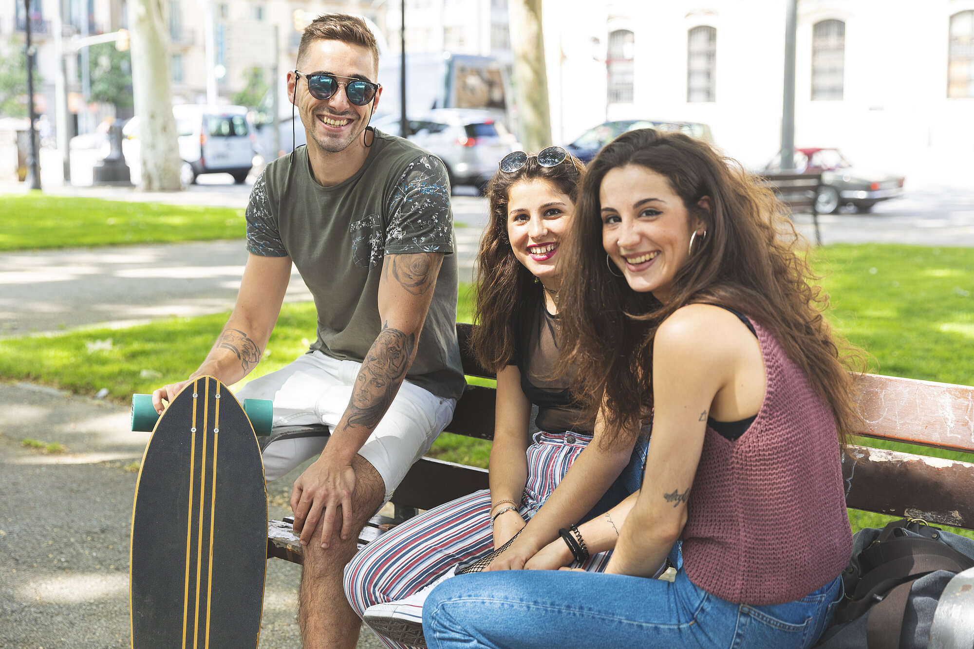 Portrait of three happy friends with skateboard relaxing in an urban park